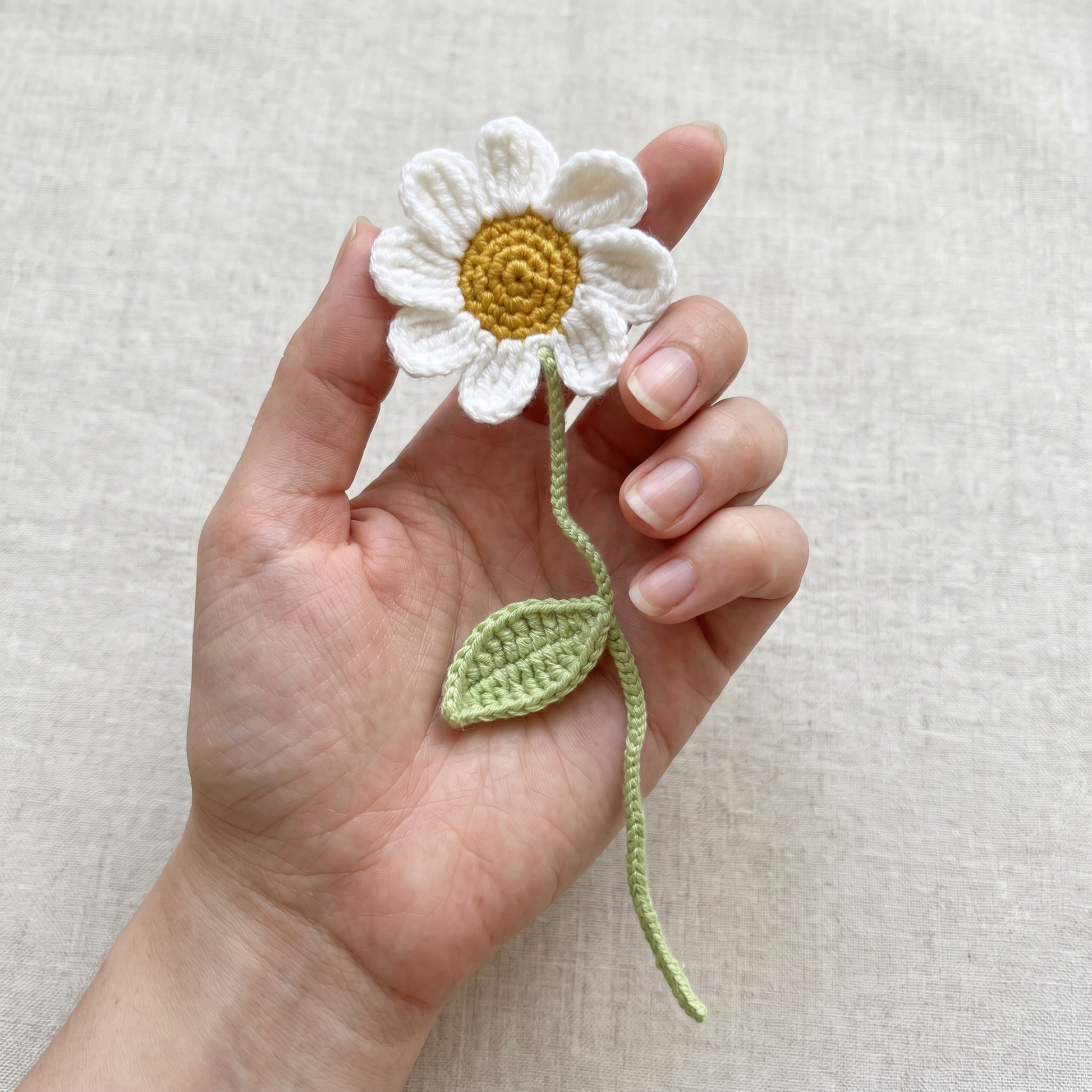 White Daisy Crochet Bookmark held in hand to show scale