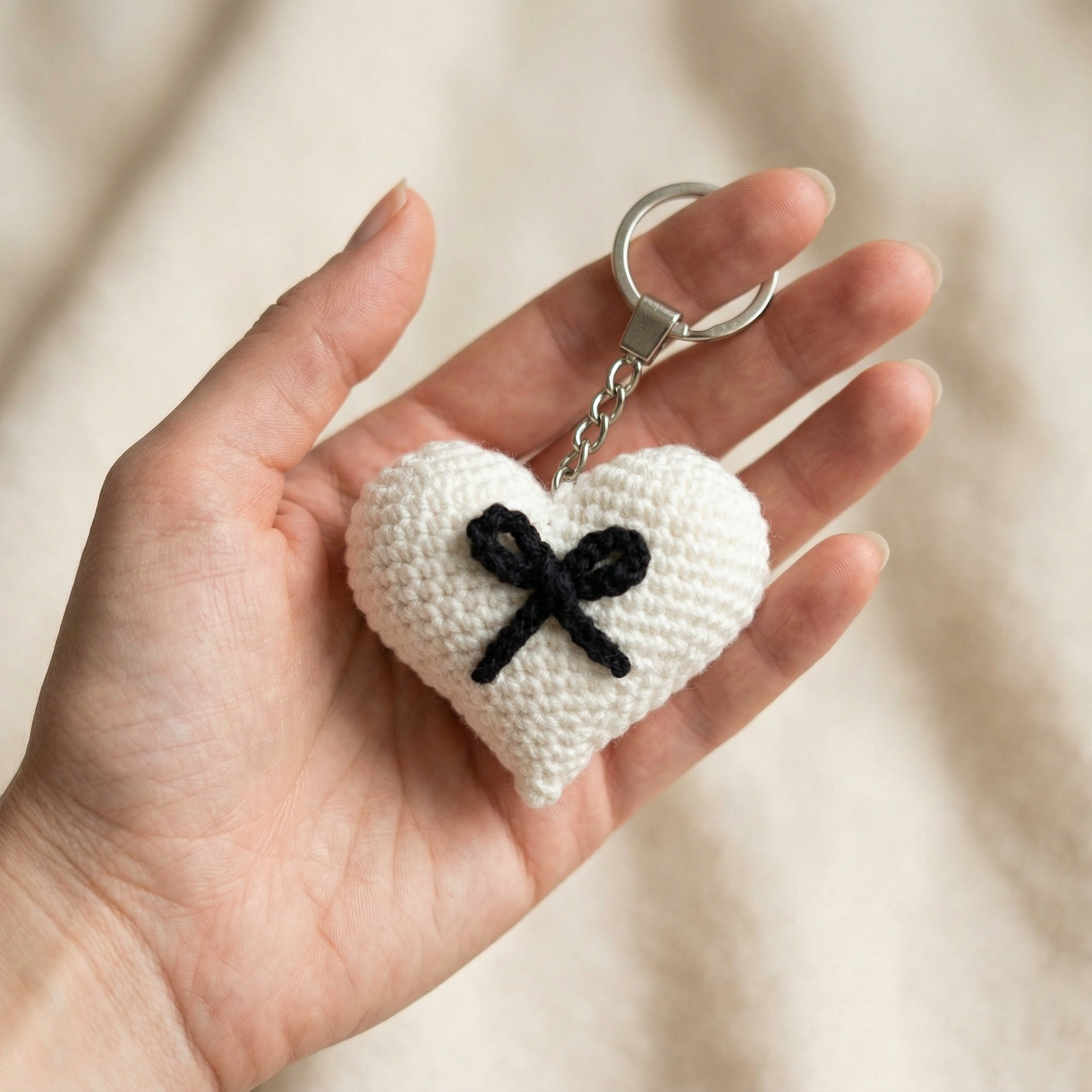 Black Bow Heart Crochet Keychain held in hand to show scale